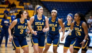 Five women basketball players in UCLA uniforms walking on a court.