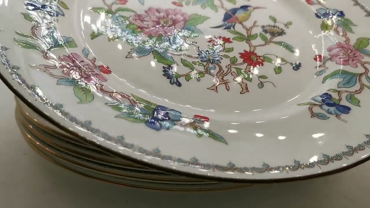 Stack of decorative porcelain plates with floral and bird designs.