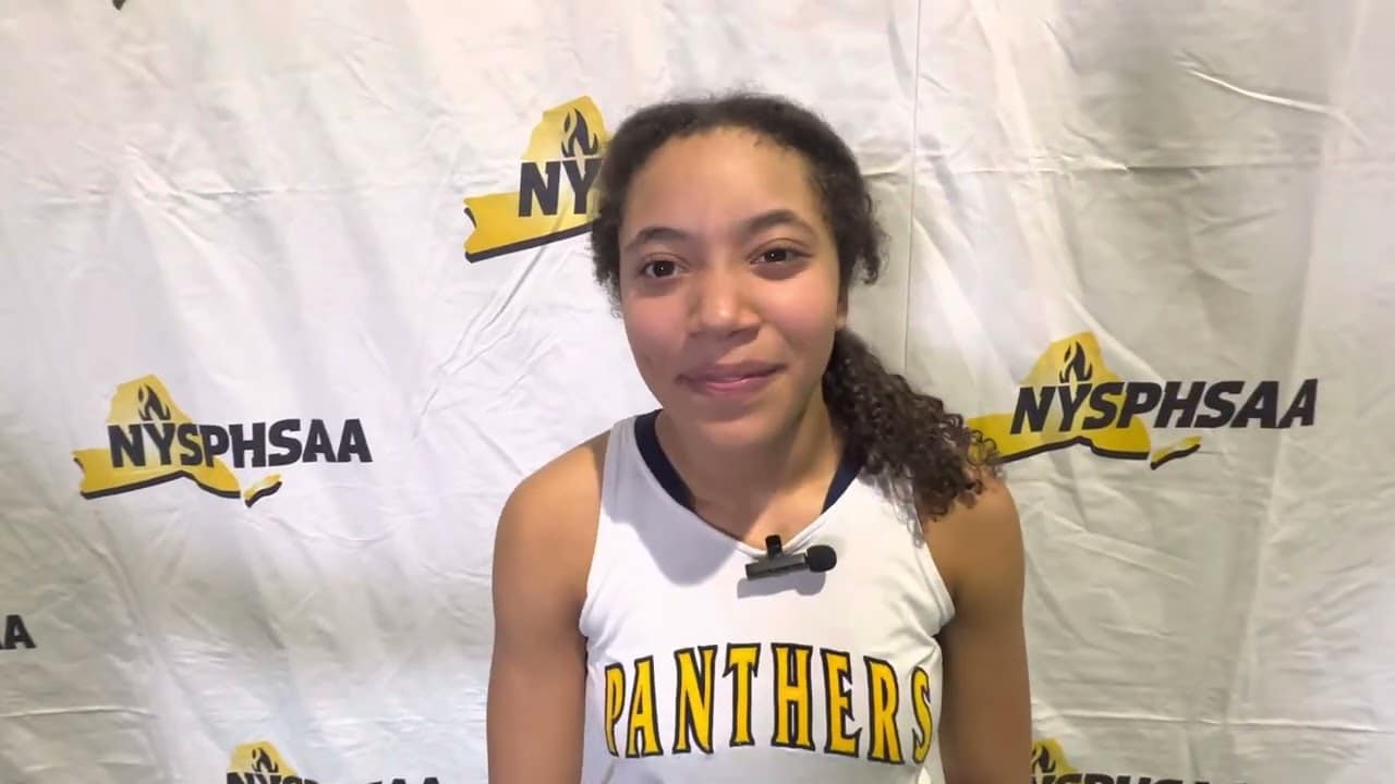 A girl in a basketball uniform stands in front of a NYSPHSAA backdrop.