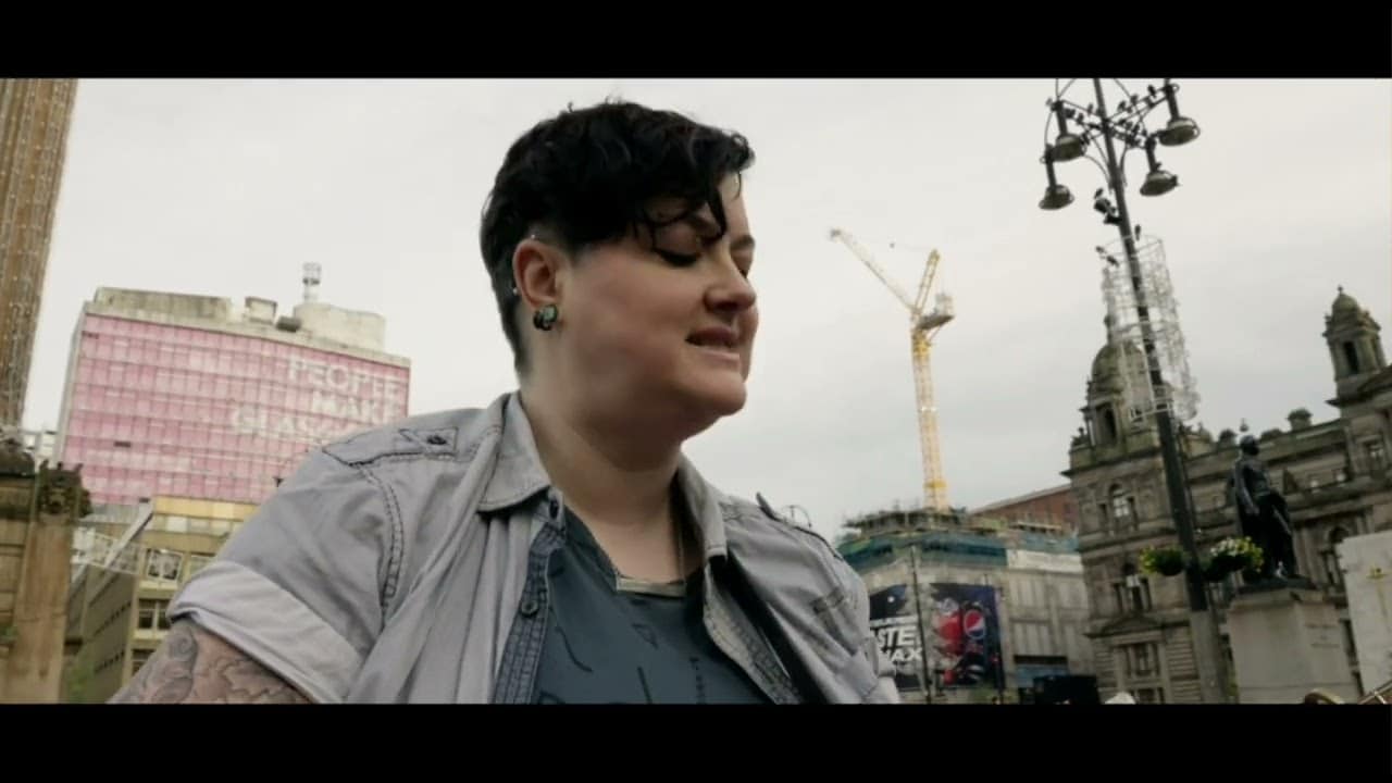 Person in a city setting with cranes and buildings in the background.