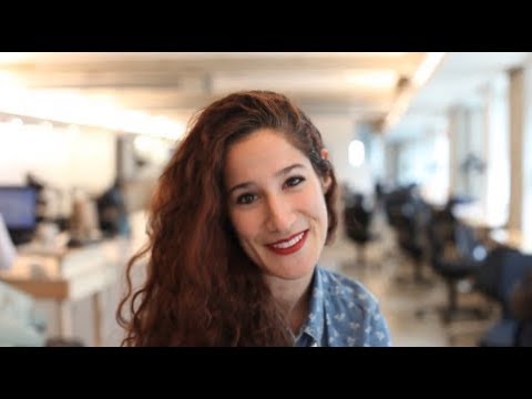 Woman with long curly hair smiling in an office setting.